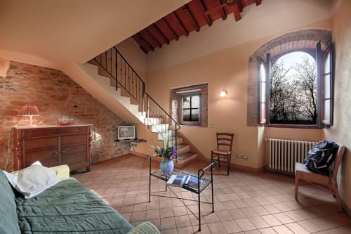Camera Pianuglia a Villa Olena a Reggello con pavimenti in terracotta, travi in legno, muri in laterizio e vista sul giardino