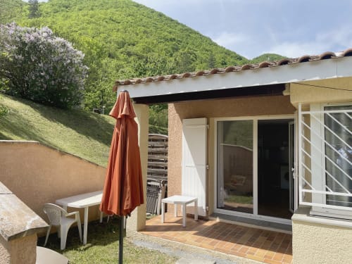 Terrasse de l'appartement LOCADIGNE à Digne-les-Bains avec parasol rouge, vue sur le jardin et panorama montagneux