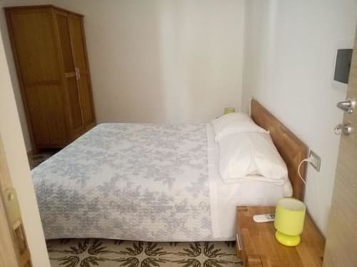 Camera accogliente dell'hotel Pescaturismo Lia a Stintino con letto in legno, cuscini bianchi e comodino