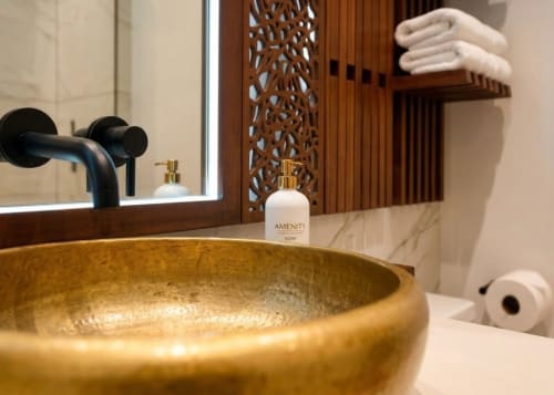 Salle de bains luxe à la Villa Merida Boutique Hotel avec vasque dorée, robinetterie noire, savon d'accueil et bois décoratif