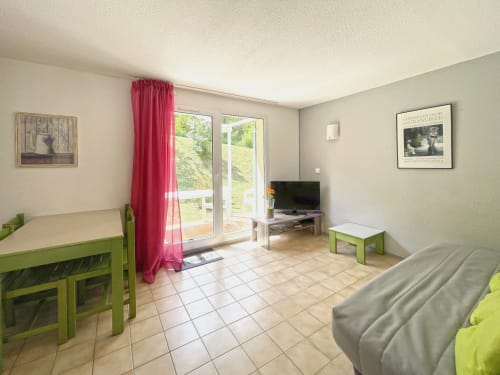 Séjour lumineux avec mobilier vert, télévision et accès à la terrasse à Digne-les-Bains