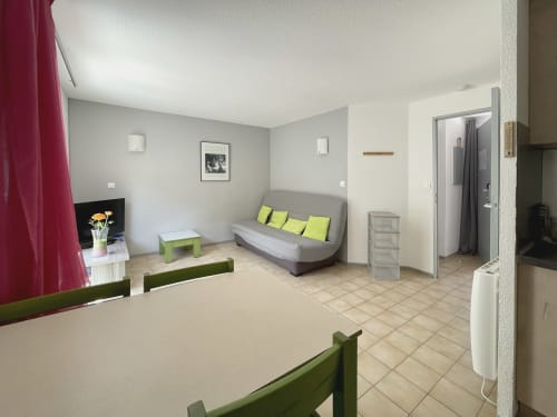 Studio lumineux et ouvert LOCADIGNE à Digne-les-Bains : canapé gris, touches anis, télévision, kitchenette, salle de bain