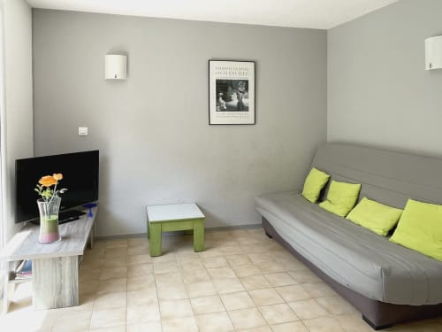 Séjour moderne de l'appartement LOCADIGNE Digne-les-Bains avec canapé, téléviseur et coussins jaune vif