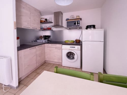 Cuisine rose avec lave-linge, réfrigérateur, micro-ondes et cuisinière dans l'appartement Vallon des Sources à l'hôtel LOCADIGNE