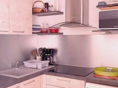 Cuisine moderne rose de l'appartement Locadigne avec cuisinière, cafetière et rangements organisés