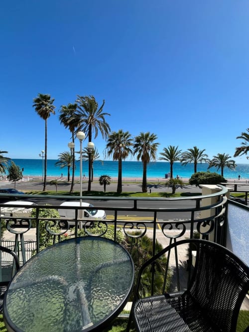 Vue depuis le balcon de l'Hôtel Flots d'Azur à Nice : la Méditerranée, palmiers et promenade de plage