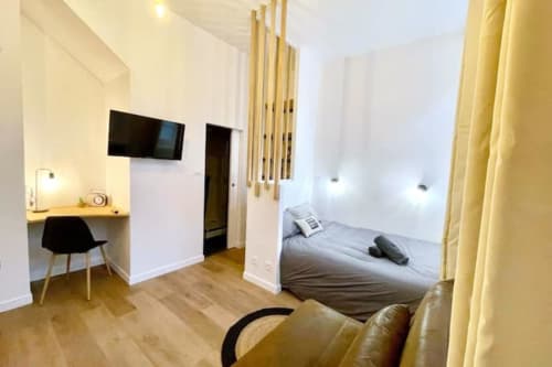 Studio moderne aux Logis d'Emma avec lit, bureau de travail, TV et rideaux jaunes en France