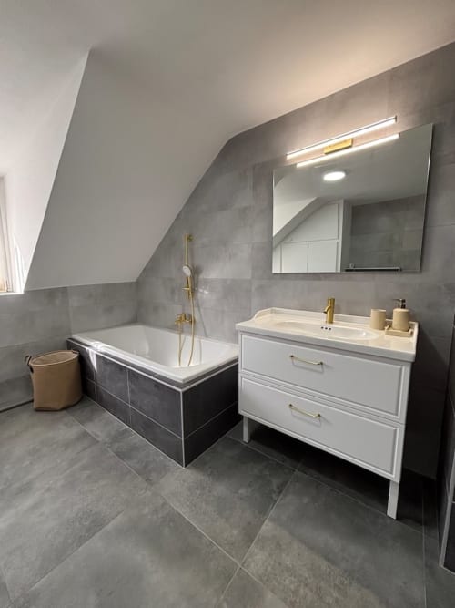 Salle de bain moderne de l'appartement Le Col'Vert aux Logis d'Emma avec baignoire, meuble vasque et sèche-serviettes électrique