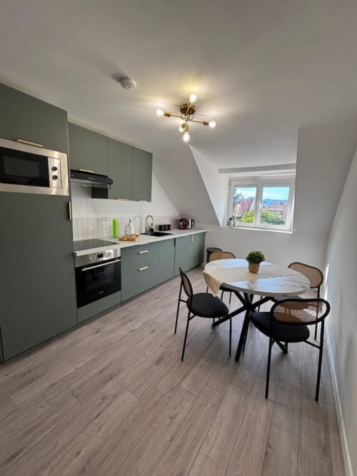 Cuisine et salle à manger du Col'Vert avec mobilier vert, électroménagers modernes et vue sur les montagnes aux Logis d'Emma