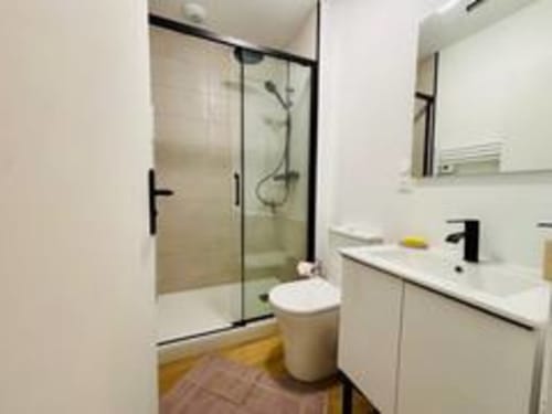 Salle de bains moderne à l'appartement Midori des Logis d'Emma avec douche vitrée, lavabo blanc et toilettes