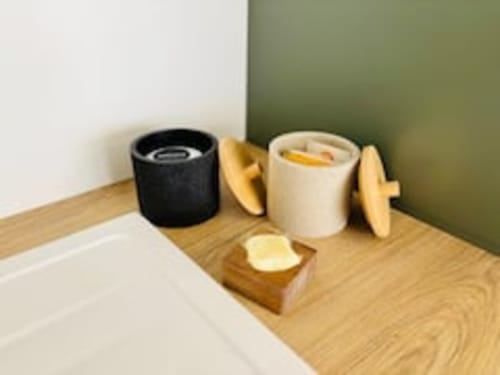 Lavabo de salle de bain avec bougies noires et crème, savonnière en bois et mur vert dans l'appartement Midori aux Logis d'Emma