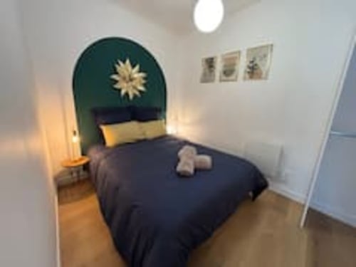Chambre moderne de l'appartement Midori à l'hôtel Les Logis d'Emma avec literie bleu foncé, tête de lit turquoise avec détail étoilé