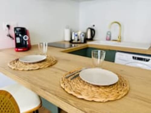 Salle à manger moderne de l'appartement Midori aux Logis d'Emma, avec table en bois, couverts et vue sur la cuisine