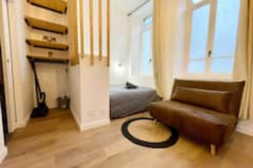 L'appartement Volta aux Logis d'Emma offre une chambre moderne avec sièges en cuir marron, parquets et vue sur la ville