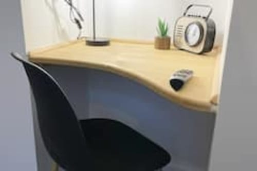 Espace de travail moderne aux Logis d'Emma avec bureau en bois clair, chaise noire, lampe de bureau, appareil photo vintage, petite plante