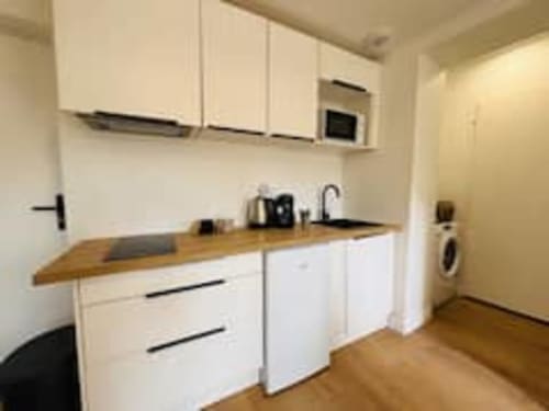 Cuisine moderne de l'appartement Terravita aux Logis d'Emma avec armoires blanches, plan de travail en bois et lave-linge