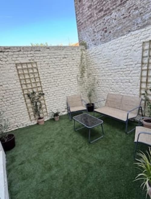 Terrasse-jardin Terravita avec espace détente, gazon synthétique et murs en brique blanche aux Logis d'Emma