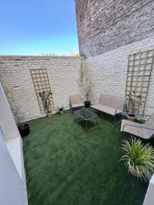 Terrasse de l'appartement Terravita aux Logis d'Emma avec gazon synthétique, salon de détente et écrans de confidentialité en treillis