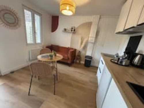 L'appartement Terravita aux Logis d'Emma offre un séjour moderne et ouvert avec cuisine, salle à manger et canapé bordeaux