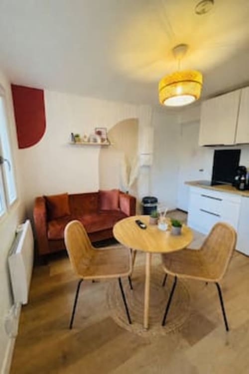 Studio moderne aux Logis d'Emma avec table à manger, canapé rouge, kitchenette et suspension jaune