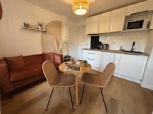 Studio moderne aux Logis d'Emma avec table à manger, canapé rouge, cuisine équipée et vue sur le jardin
