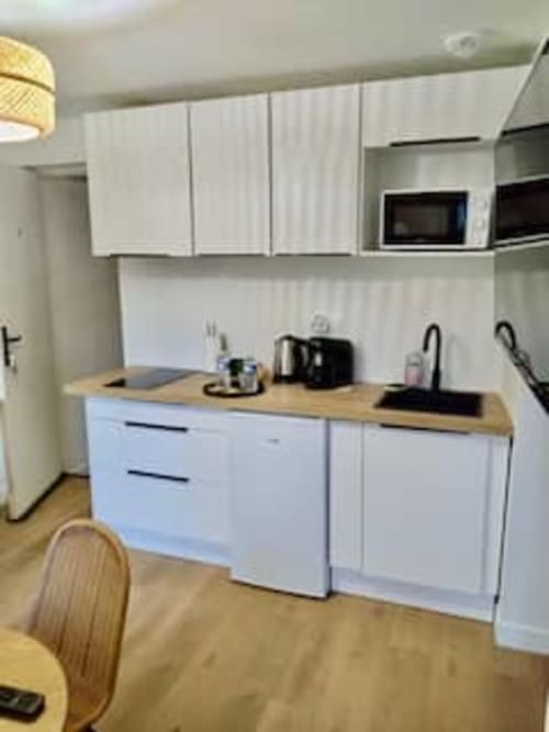 Cuisine moderne blanche dans l'appartement Terravita aux Logis d'Emma avec plans de travail en bois et électroménagers