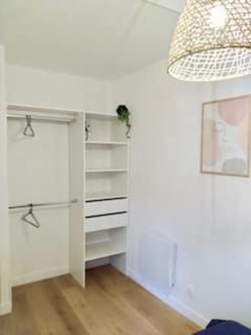 Dressing élégant aux rangements blancs intégrés, cintres et tiroirs à l'appartement Les Logis d'Emma en France