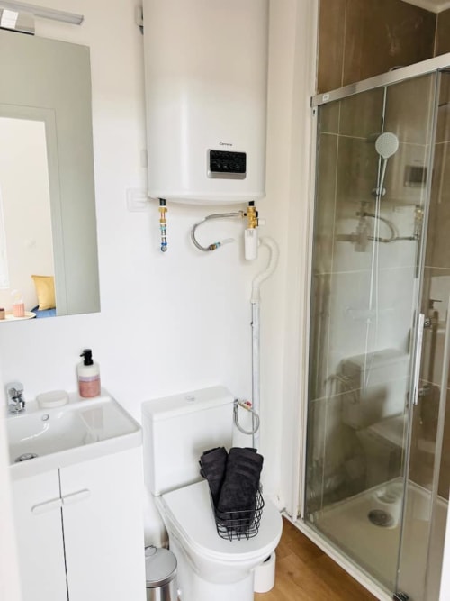 Salle de bain moderne de l'appartement Yogi aux Logis d'Emma avec vasque blanche, toilettes et douche vitrée