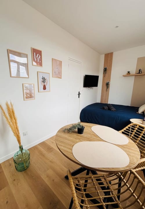 Chambre studio moderne aux Logis d'Emma : mobilier en bois, lit bleu marine, décoration murale et TV écran plat