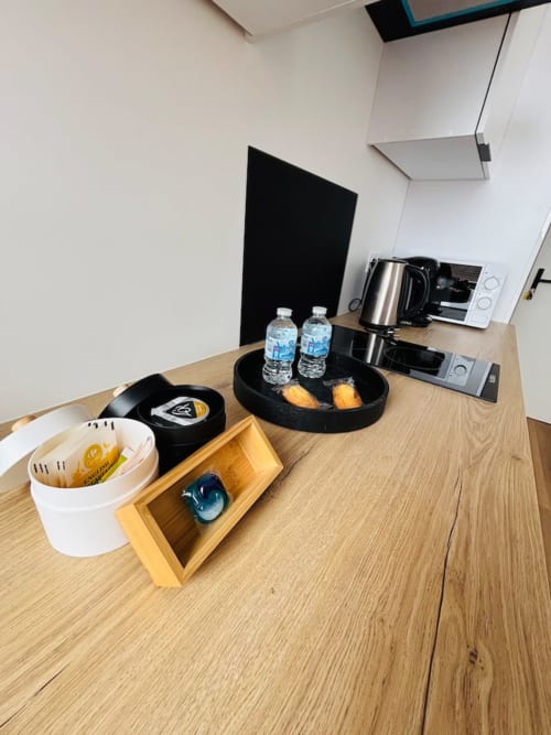 Plateau de bienvenue dans l'appartement Yogi aux Logis d'Emma avec bouteilles d'eau, pâtisseries et kitchenette