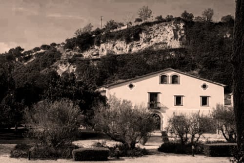 Hotel Restaurante Can Carol en Capellades, España - villa de color crema con olivos y colinas de piedra caliza de fondo