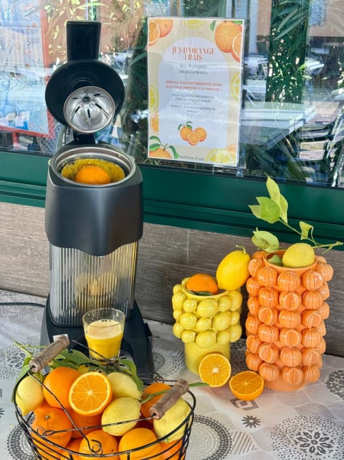 Présentation de jus d'orange frais à l'Hôtel Reine D'Azur avec machine à jus et agrumes.