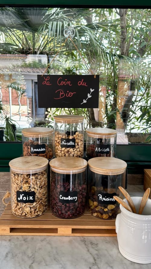 Présentation de petit-déjeuner bio avec pots étiquetés de fruits secs, céréales et noix à l'Hôtel Reine D'Azur, Roquebrune-Cap-Martin