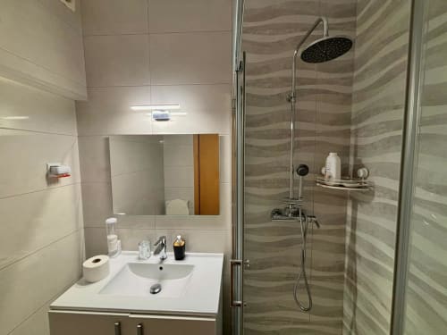 Banheiro moderno do hotel Al Mare Ocean View em Albufeira com pia, espelho, chuveiro tipo chuva e paredes com azulejos listrados