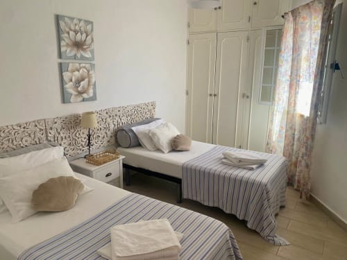 Quarto twin no hotel Al Mare Ocean View em Albufeira com roupa de cama listrada azul e vista para a cidade