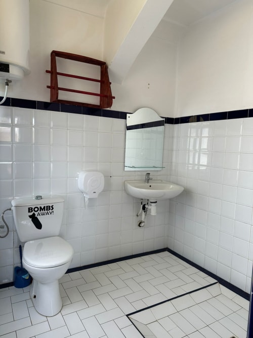 Clean bathroom in Namasté room at Yousurf Surfhouse hostel, Essaouira with toilet, sink, mirror and white tile walls