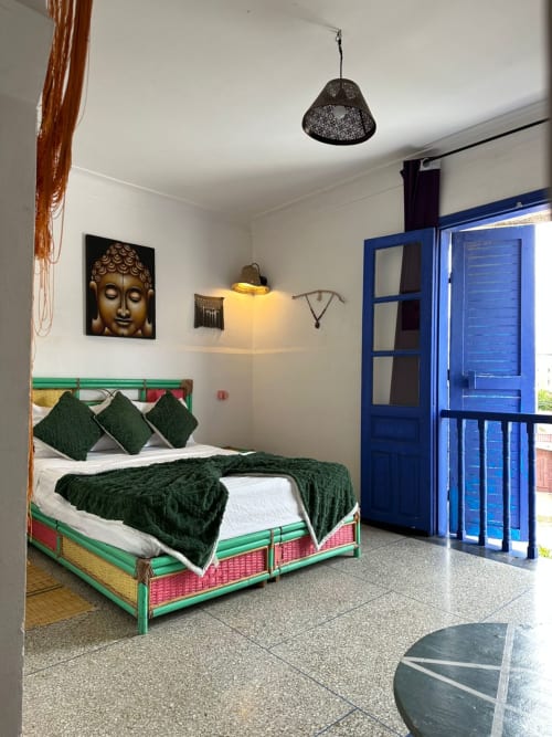 Colorful bedroom at Yousurf Surfhouse hostel in Essaouira with green bed, blue doors, and Buddha artwork