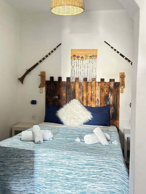 Berber room at Yousurf Surfhouse hostel in Essaouira with wooden pallet headboard, blue bedding, white pillows, and surfboard