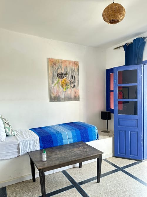Bright Berber room at Yousurf Surfhouse in Essaouira with blue bed, modern furnishings and wicker pendant light