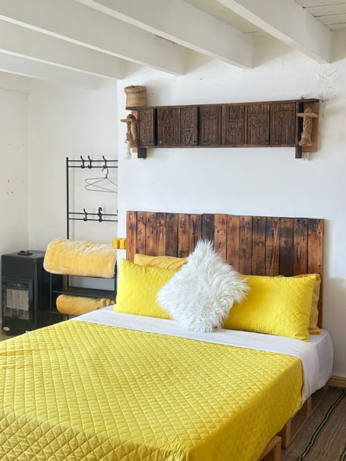 Bright yellow bedding in Sahara room at Yousurf Surfhouse hostel in Essaouira with wooden headboard and city view