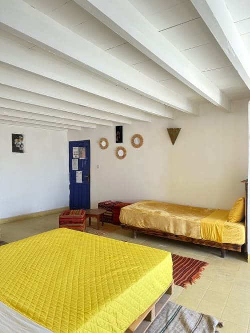 Bright Sahara room at Yousurf Surfhouse hostel in Essaouira with yellow beds, exposed beams, and Moroccan décor