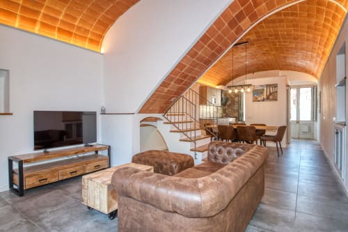 Moderna zona de estar en loft de Finques Garcia Enrich, Palafrugell, con techo abovedado de ladrillo terracota y cuero marrón