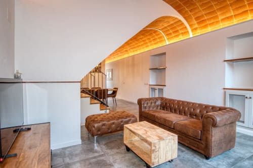 Salón moderno en Finques Garcia Enrich en Palafrugell con sofá de cuero marrón, mesa de madera e iluminación de techo curvo