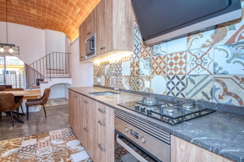 Cocina moderna con azulejos estampados, muebles de madera y electrodomésticos de acero inoxidable en Finques Garcia Enrich, Palafrugell