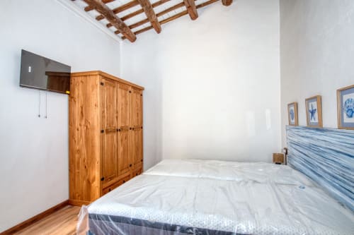 Dormitorio amplio en Finques Garcia Enrich en Palafrugell con armario de madera, cabecero azul y vigas vistas