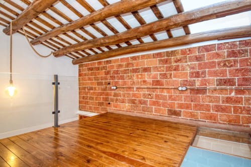 Loft moderno con pared de ladrillo visto, vigas de madera y suelos de madera pulida en Finques Garcia Enrich, Palafrugell