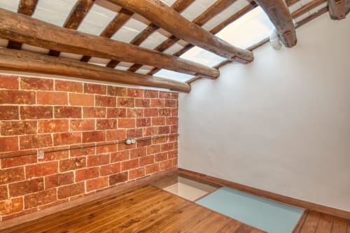 Habitación rústica en Finques Garcia Enrich con pared de ladrillo visto, vigas de madera y suelo de parquet en Palafrugell