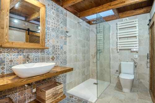Baño moderno en Finques Garcia Enrich, Palafrugell con azulejos decorativos, vigas de madera, lavabo de cerámica y ducha abierta