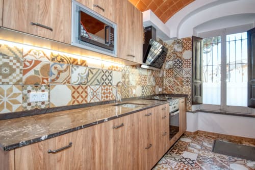 Cocina moderna con azulejos estampados, muebles de madera y encimeras de granito en Finques Garcia Enrich, Palafrugell