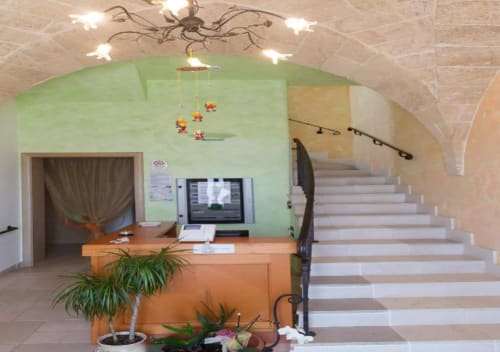 Zona reception di B&B Villa Arneide a Torre Lapillo con scrivania arancione, parete verde accent, scala e piante